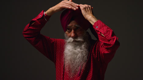 Low-Key-Studio-Lighting-Shot-Of-Senior-Sikh-Man-With-Beard-Tying-Fabric-For-Turban-Against-Dark-Background-13